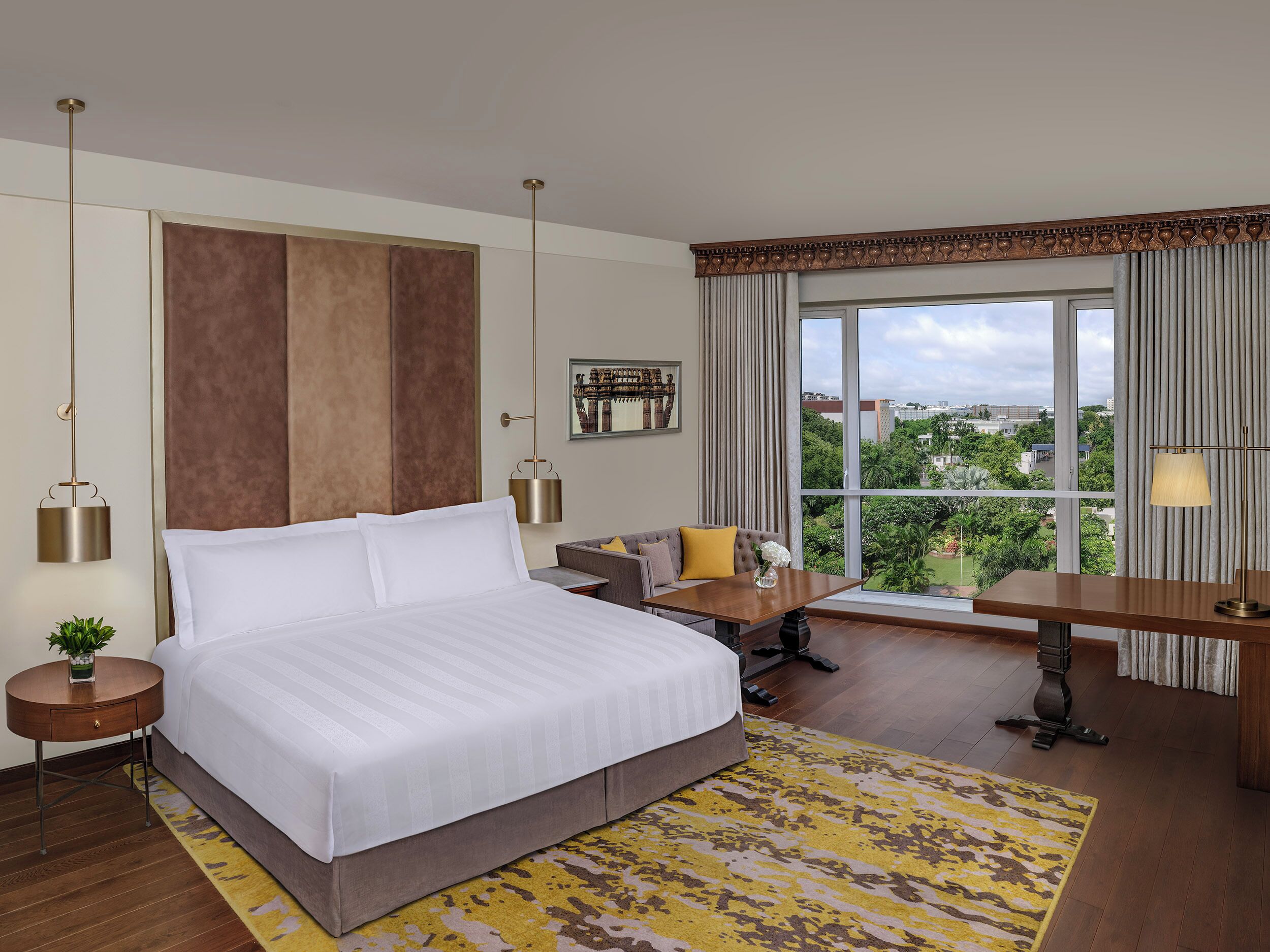 Habitación de hotel con una cama grande, un escritorio, un sofá y vistas a la ciudad.