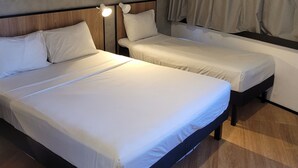A hotel room with two beds, a headboard, a nightstand with a lamp, and a window with curtains. - Ibis Maceio Pajucara (Maceió)