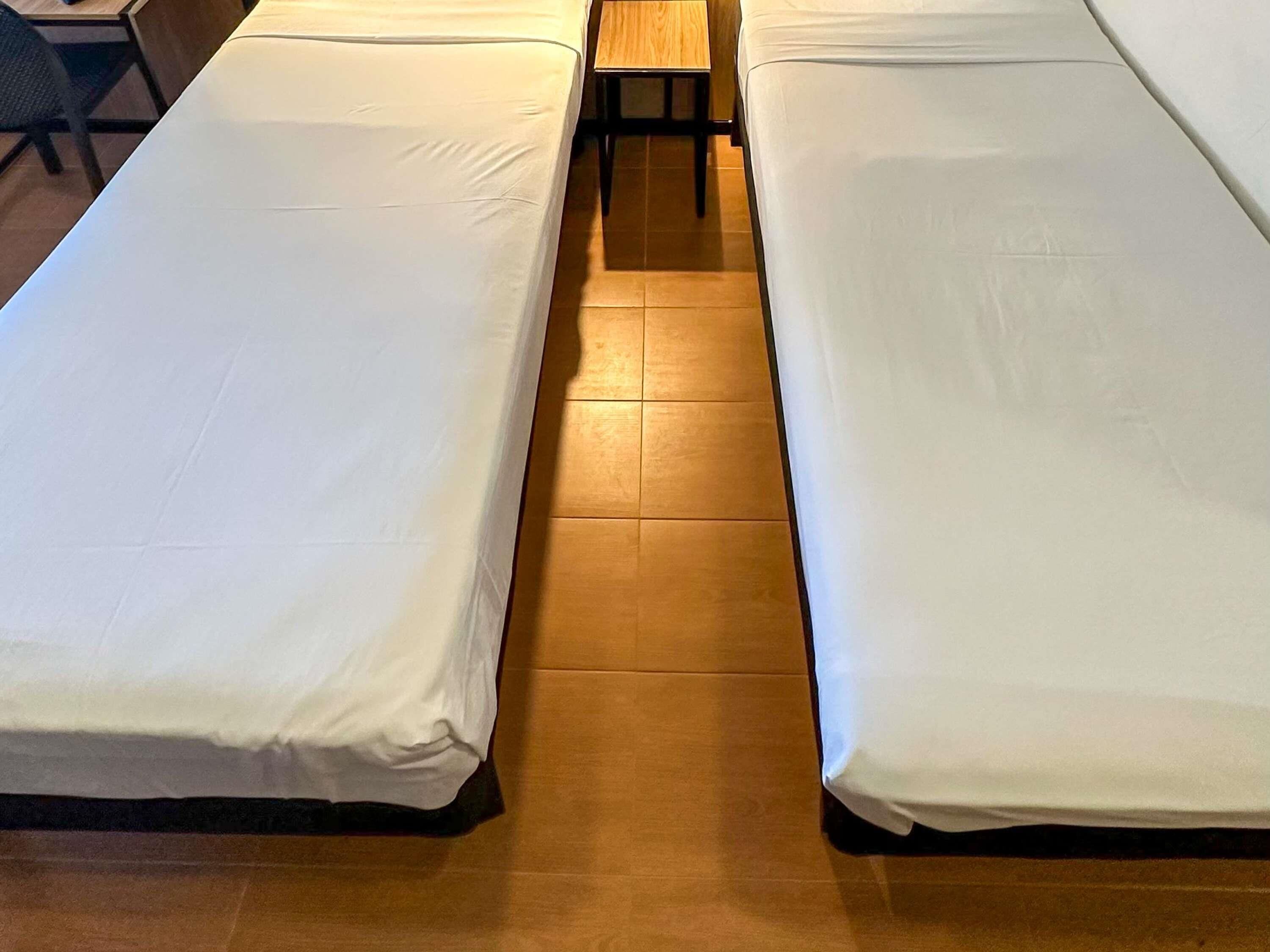 A room with two single beds, a wooden table, and a chair.