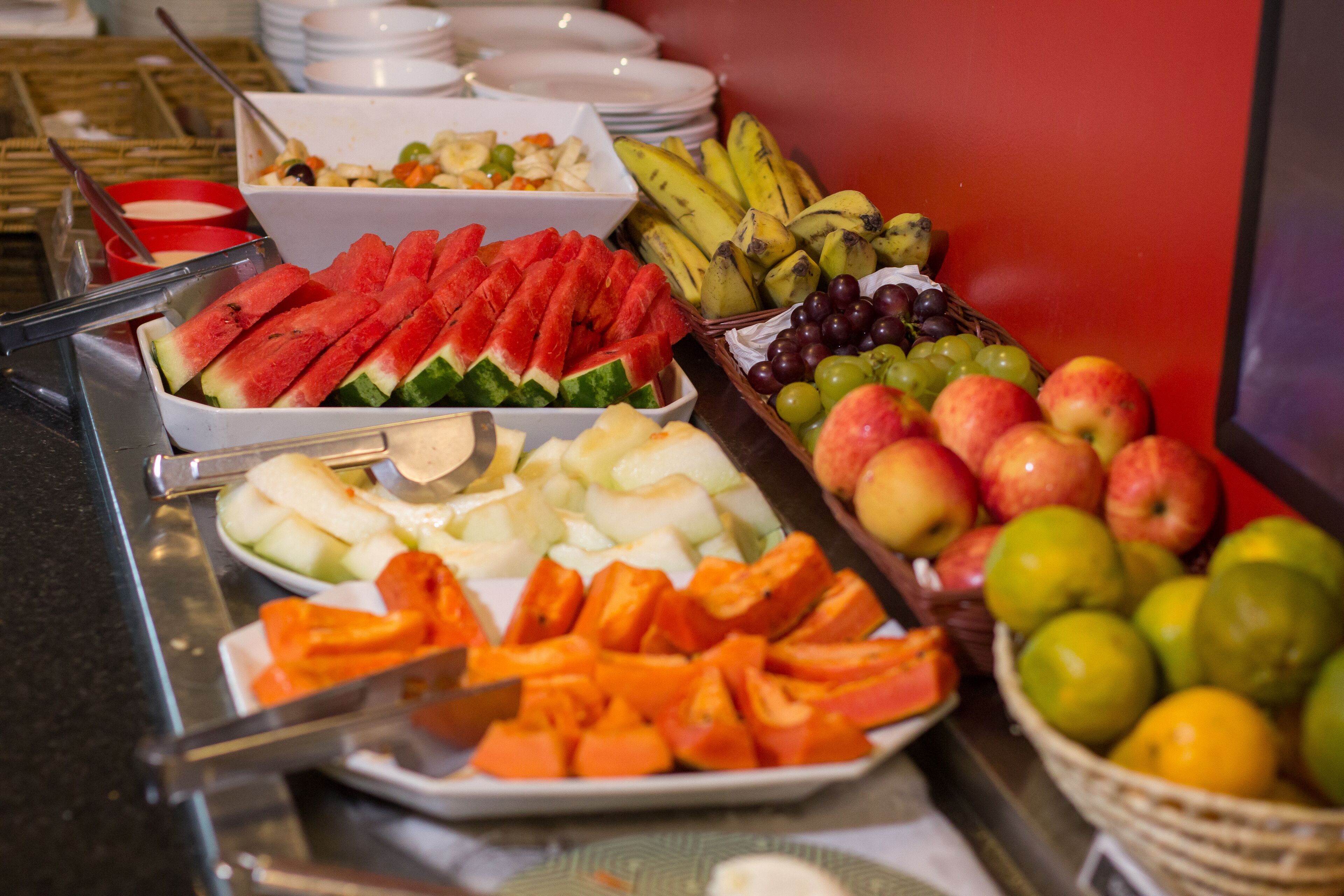 Un bufé con diversas frutas y verduras, entre ellas sandía, manzanas y uvas.