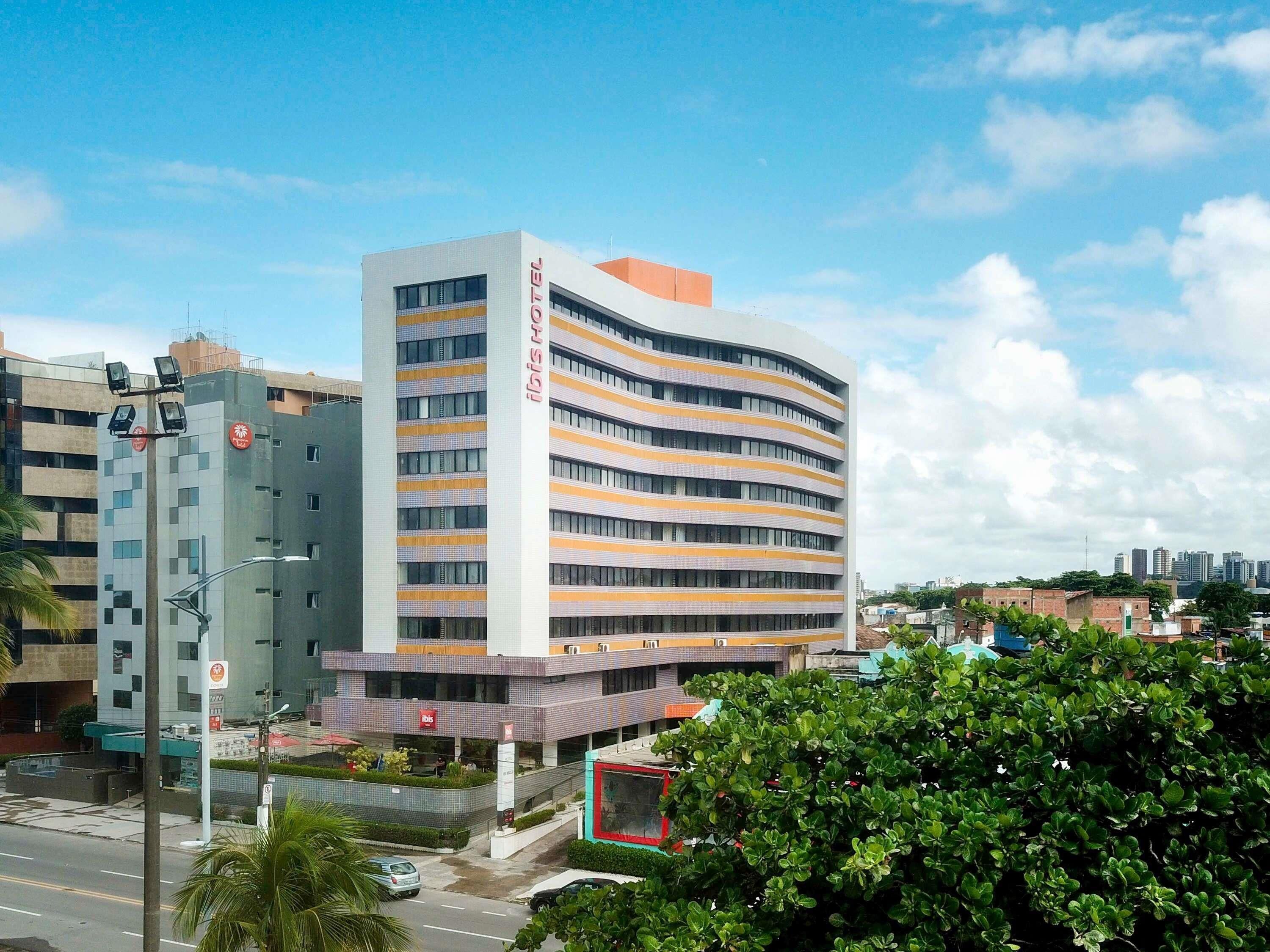 A multi-story hotel with a curved facade, a prominent entrance, and a parking area in front.
