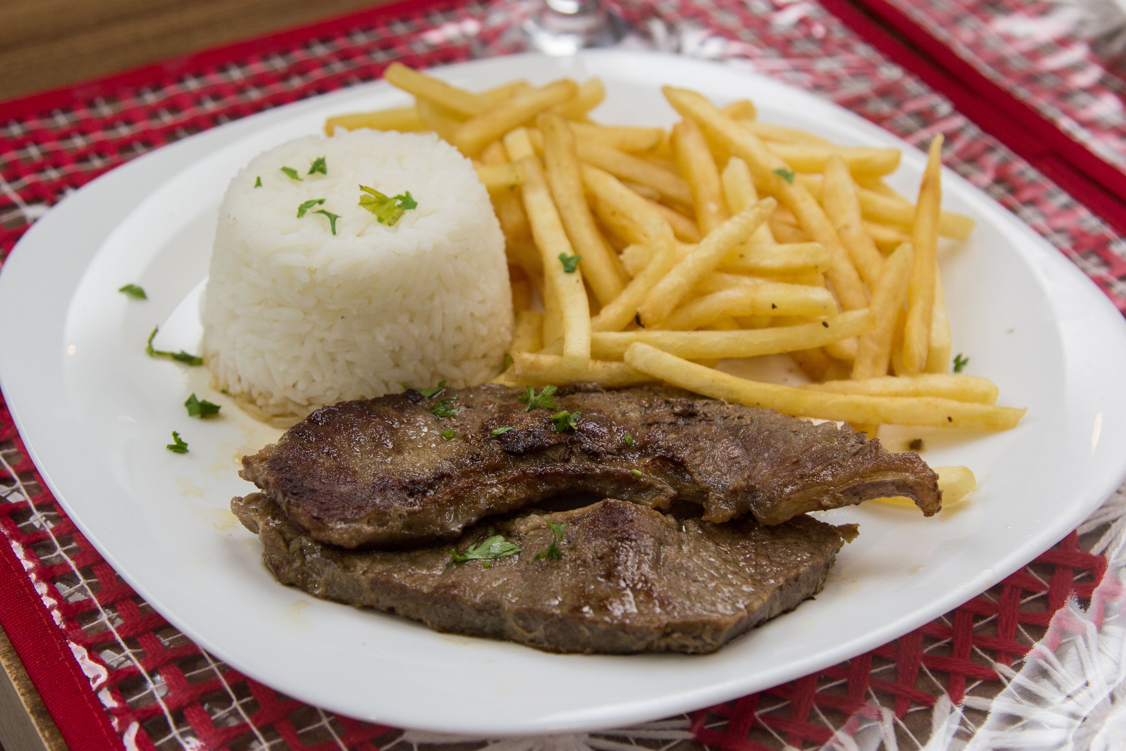 A plate with white rice, French fries, and grilled meat.