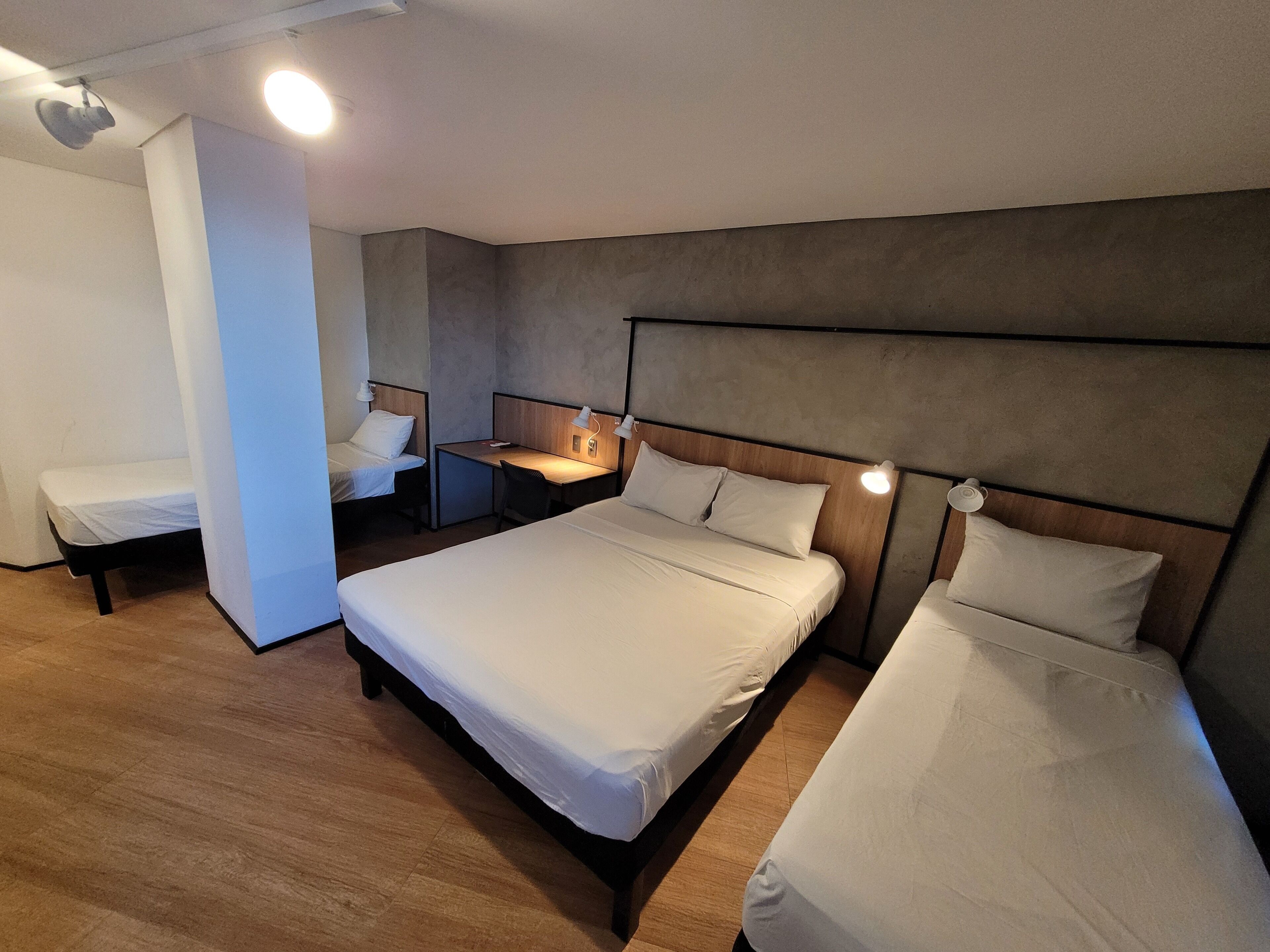 A hotel room with a large bed, a smaller bed, a desk, and a chair.