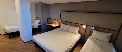 A hotel room with a large bed, a smaller bed, a desk, and a chair.