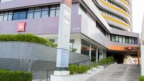 A modern hotel with a prominent 'ibis' sign, a curved facade, and a staircase leading to the entrance. - Ibis Maceio Pajucara (Maceió)