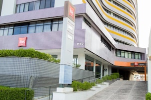 Un hotel moderno con un llamativo letrero de 'ibis', fachada curva y una escalera que conduce a la entrada.