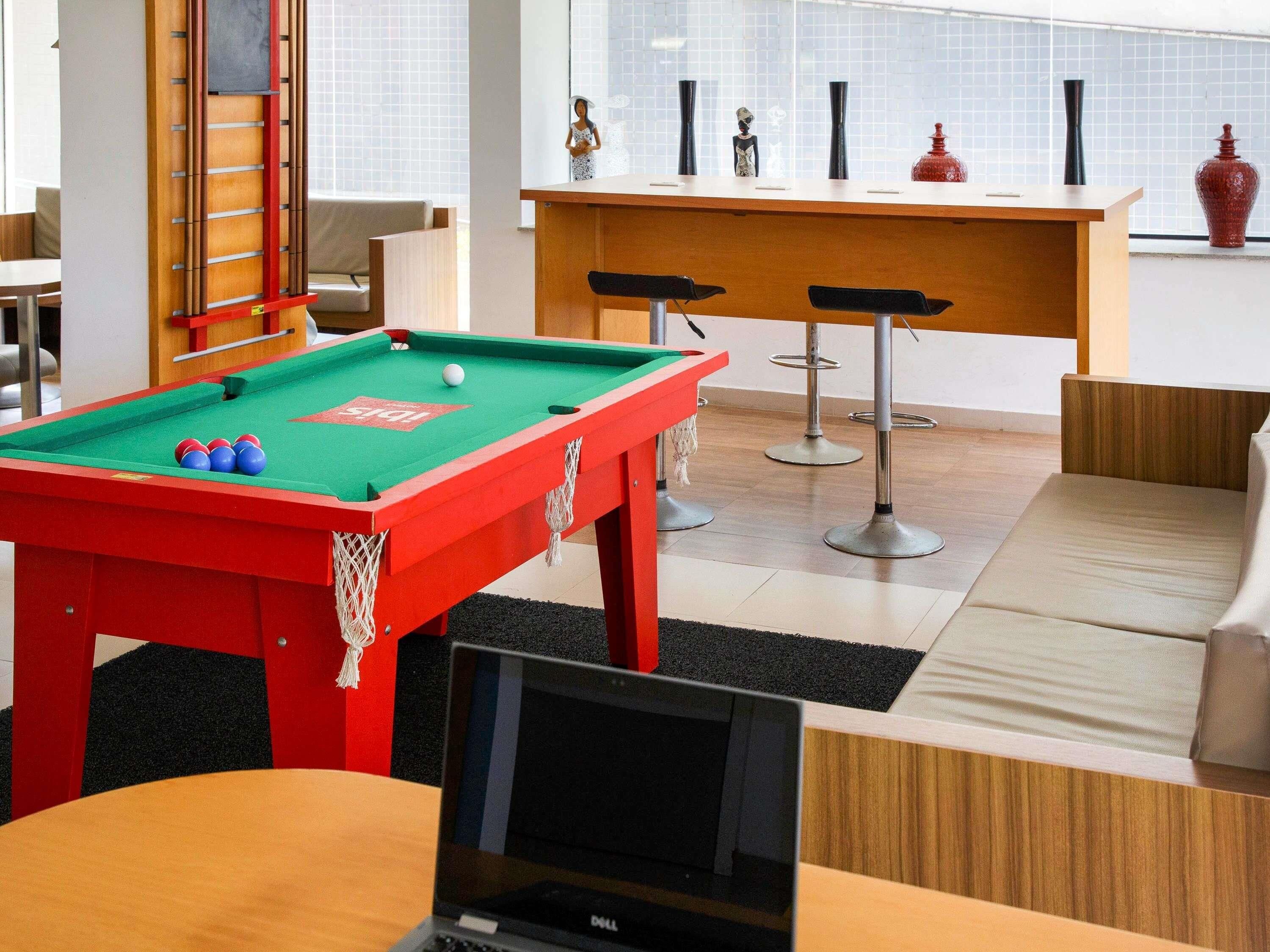A pool table with balls, a laptop, and a bar area with stools.