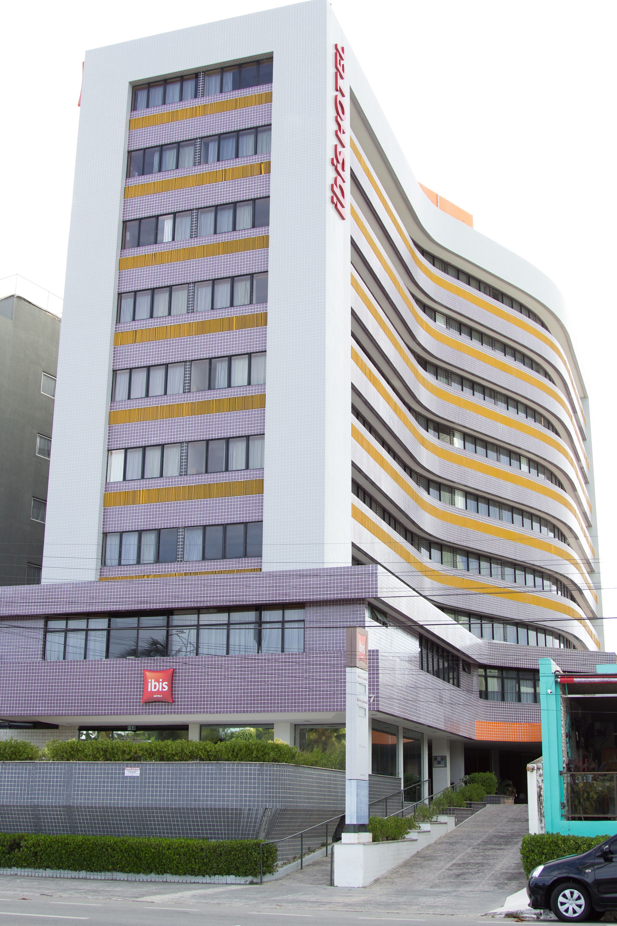 Un hotel moderno con fachada curva, varios pisos y señalización llamativa.