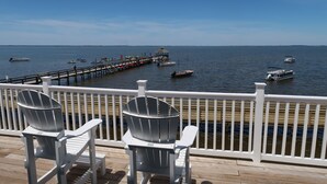 Une terrasse en bois avec deux fauteuils Adirondack donnant sur une jetée qui s’avance dans une étendue d’eau calme.