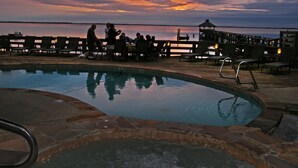A pool area with a wooden deck, lounge chairs, and a view of the water. - The Inn At Corolla Light (Corolla)