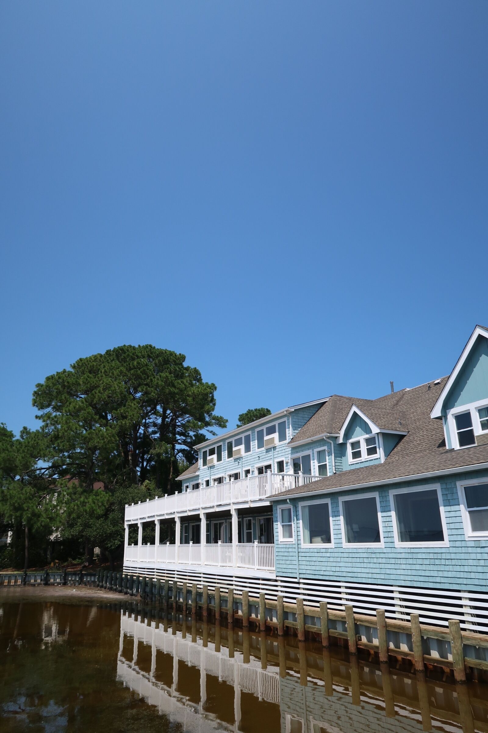 A row of blue and white waterfront houses with a dock extending into a calm body of water.