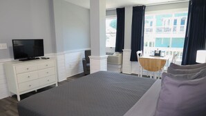 A hotel room with a bed, a TV on a dresser, a small table with chairs, and a balcony with curtains. - The Inn At Corolla Light (Corolla)