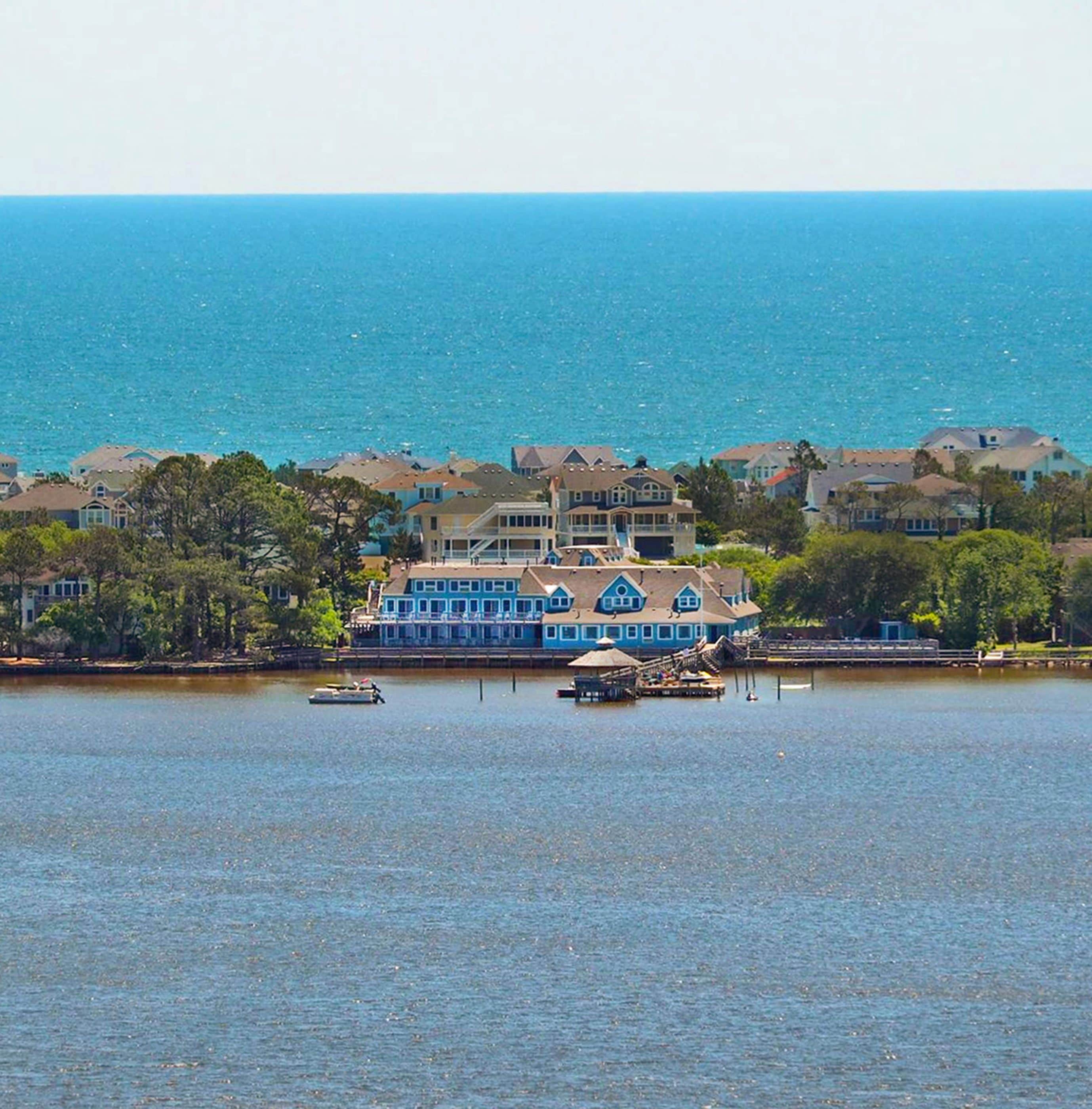 Une propriété située au bord de l’eau, avec une grande maison à plusieurs niveaux et une façade bleue remarquable.