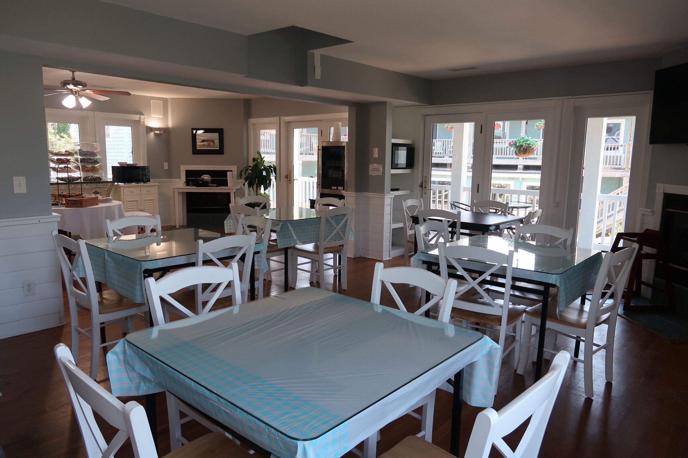 A dining area with white chairs and a glass table, a kitchen with white cabinets, and a balcony with a view.