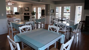 Un coin repas avec des chaises blanches et une table en verre, une cuisine avec des meubles blancs et un balcon offrant une vue.
