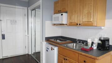 A kitchen with wooden cabinets, a microwave, a refrigerator, a sink, and a coffee maker.