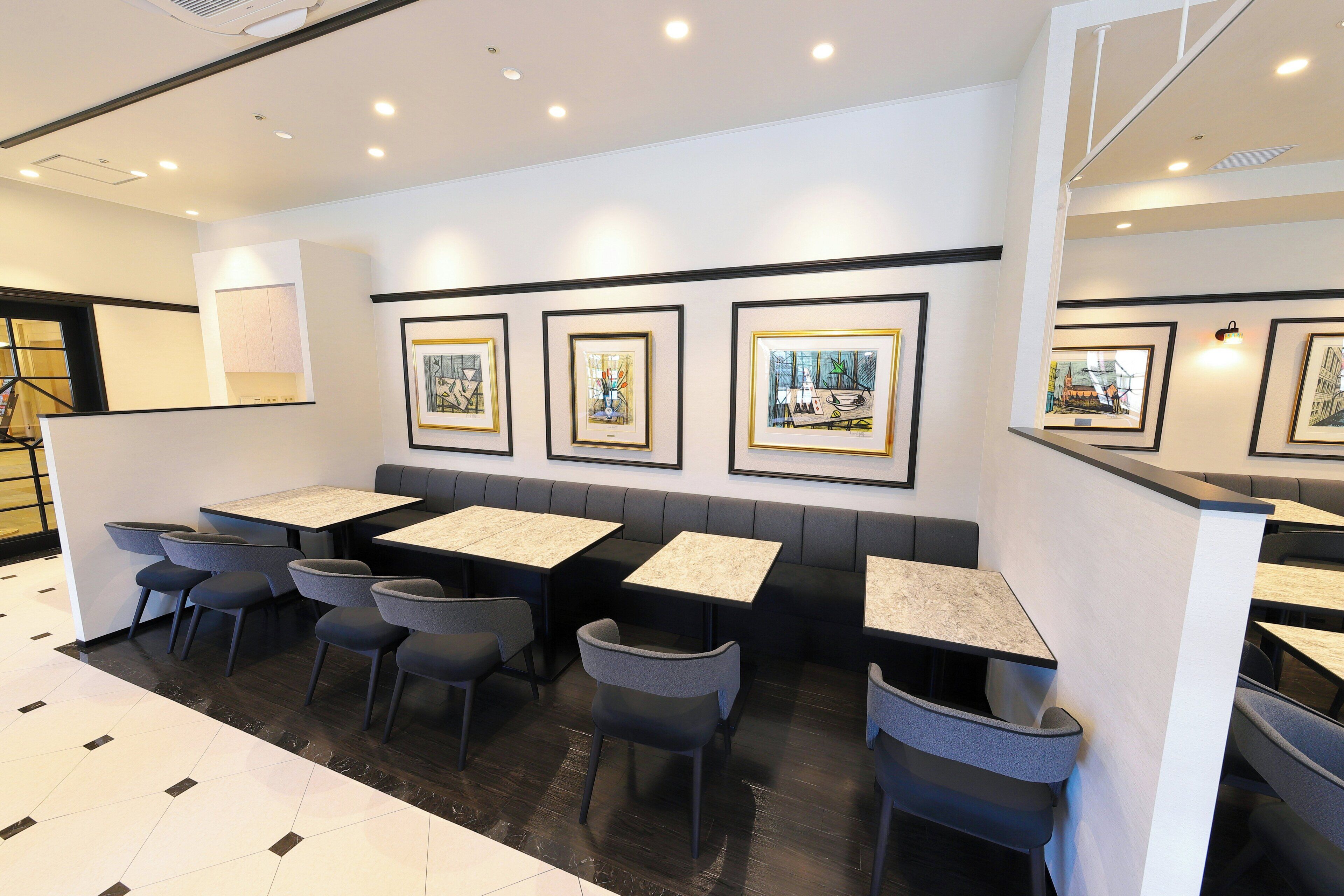 A restaurant interior with booths, tables, and framed artwork on the walls.