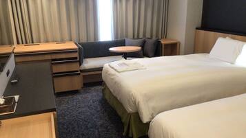 Una habitación de hotel con cama, escritorio, silla y una mesita.