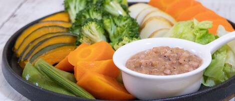 A plate with sliced vegetables and a bowl of bean soup.