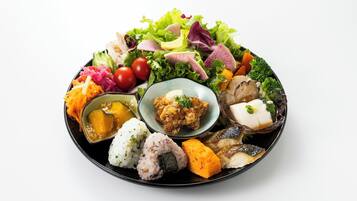 Un plato redondo negro con diferentes alimentos, como arroz, verduras y una ensalada.