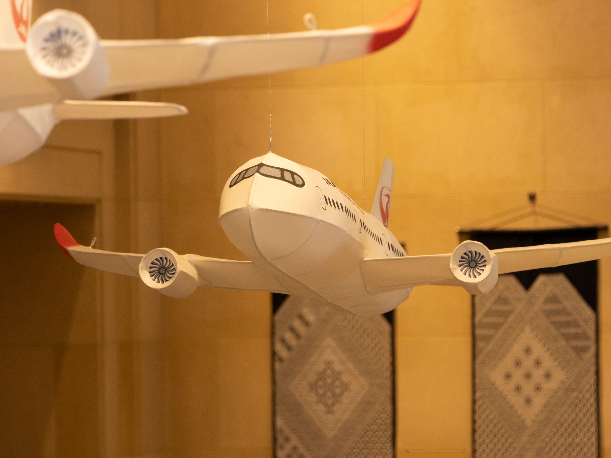 Un modèle d’avion suspendu dans une pièce dont les murs sont décorés de motifs.