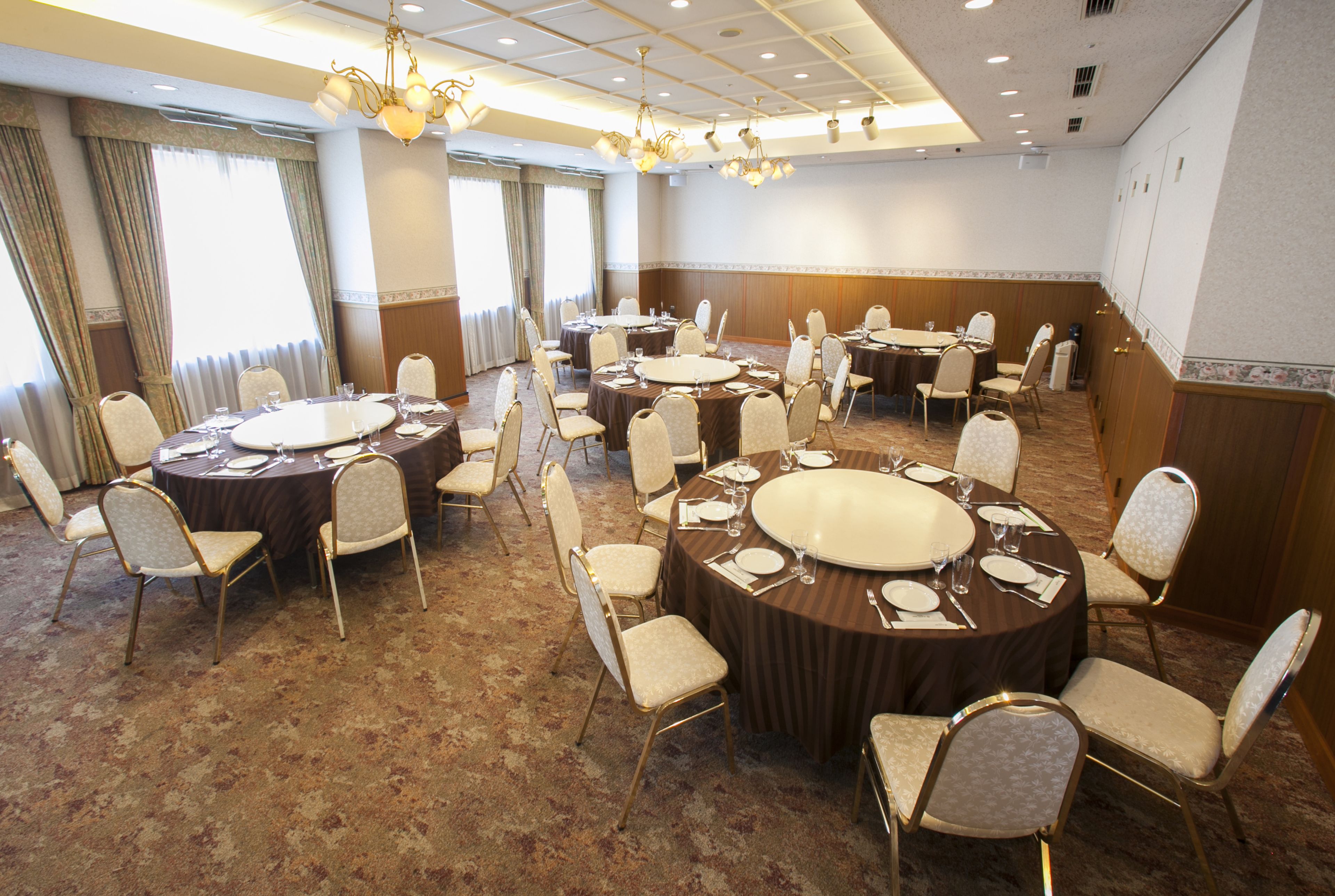 A conference room with multiple round tables, each set with chairs and dining essentials.
