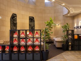 Un hall con zona de estar, una planta y una escultura en la pared.