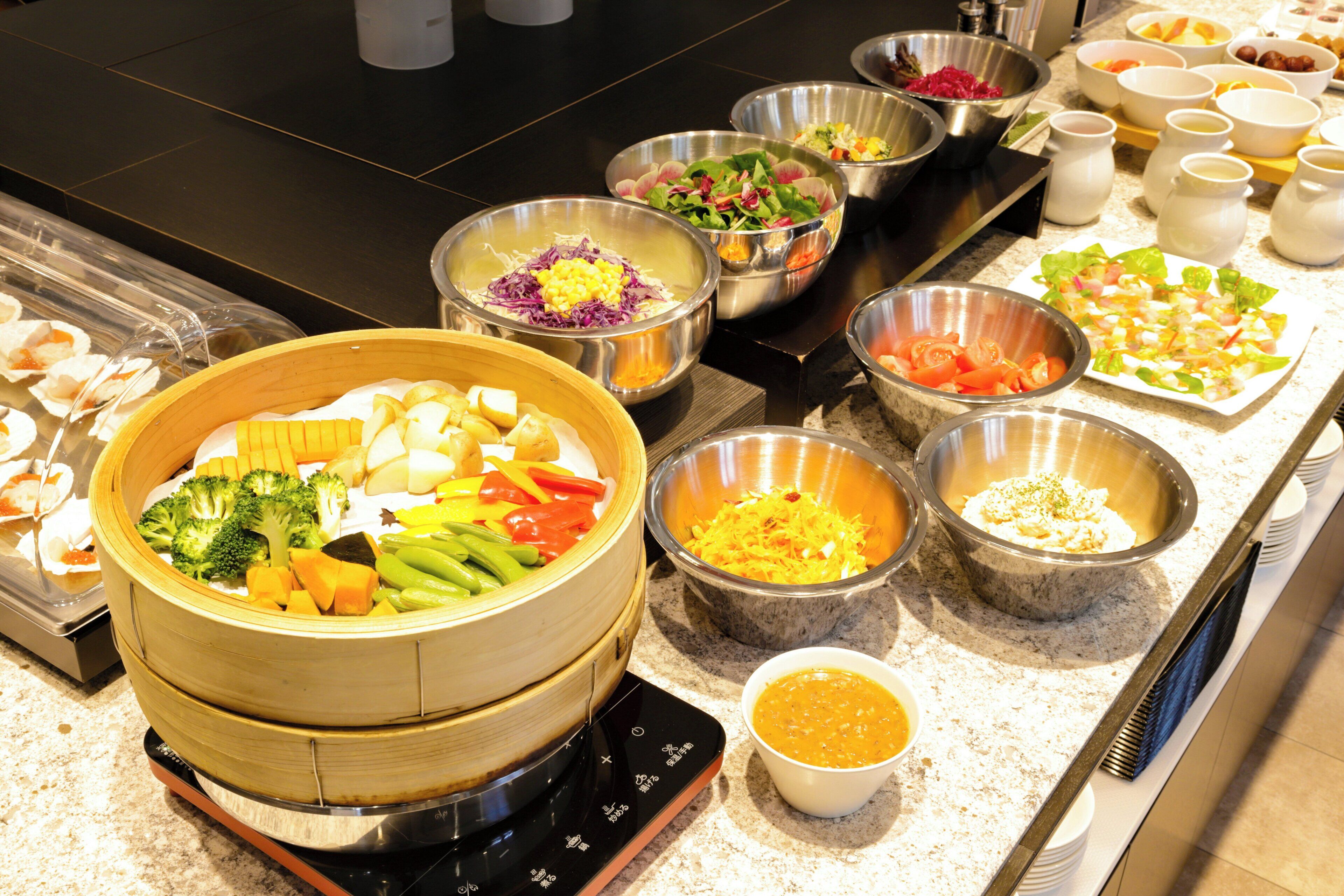 A buffet with various food items and a steaming hot pot.