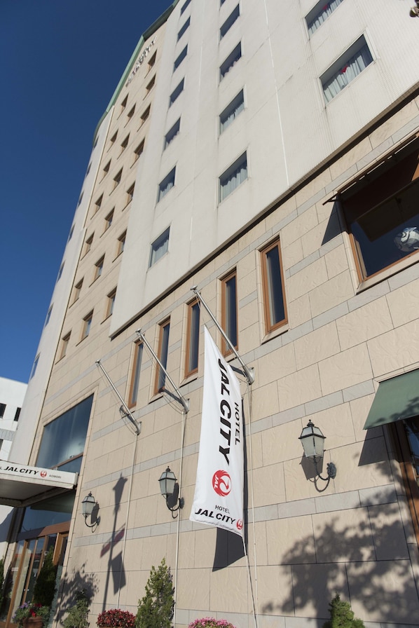Un edificio de hotel alto con un cartel llamativo que dice "JAL CITY" y un logo.
