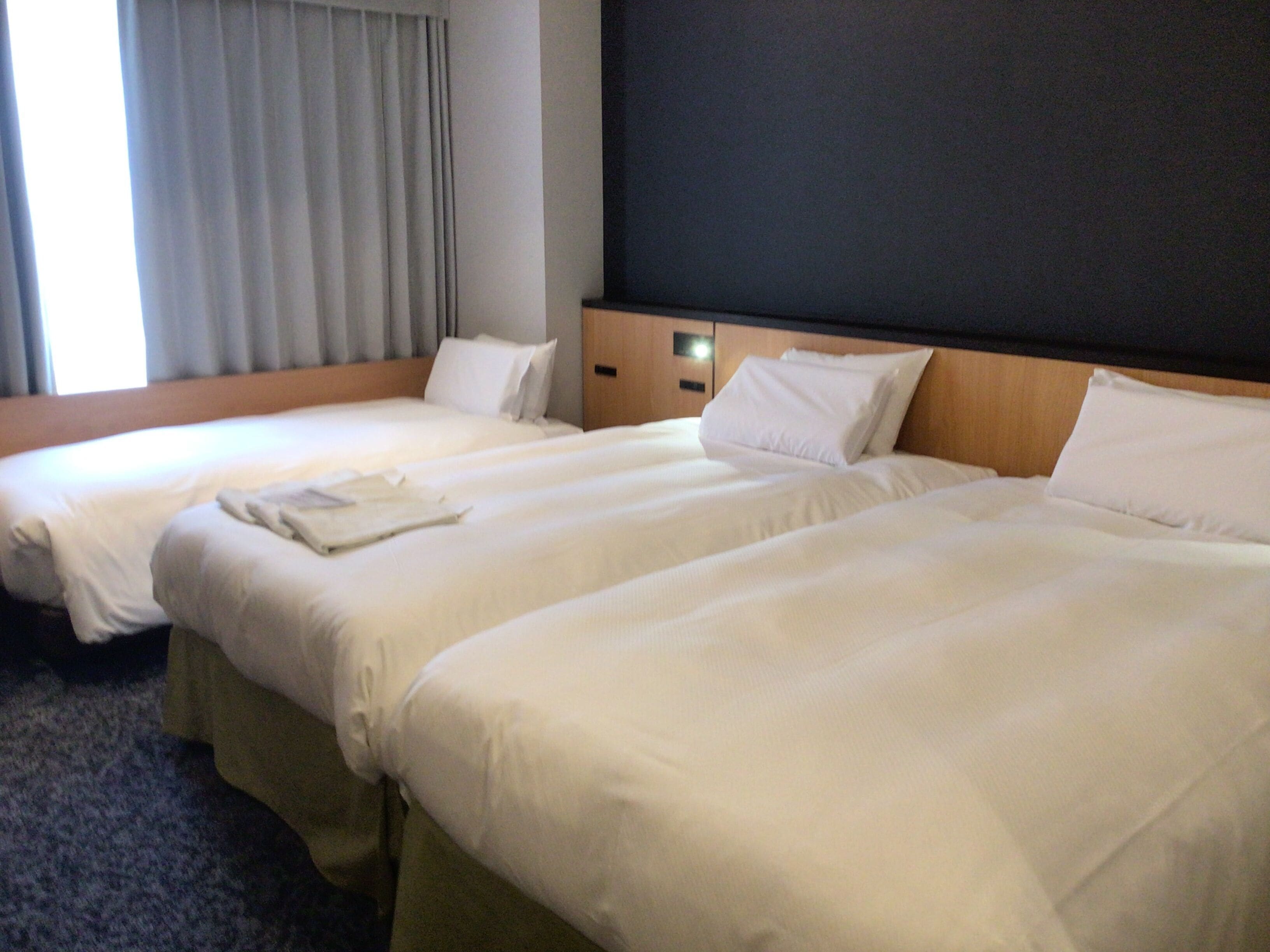 A hotel room with two beds, a wooden headboard, and a window with curtains.