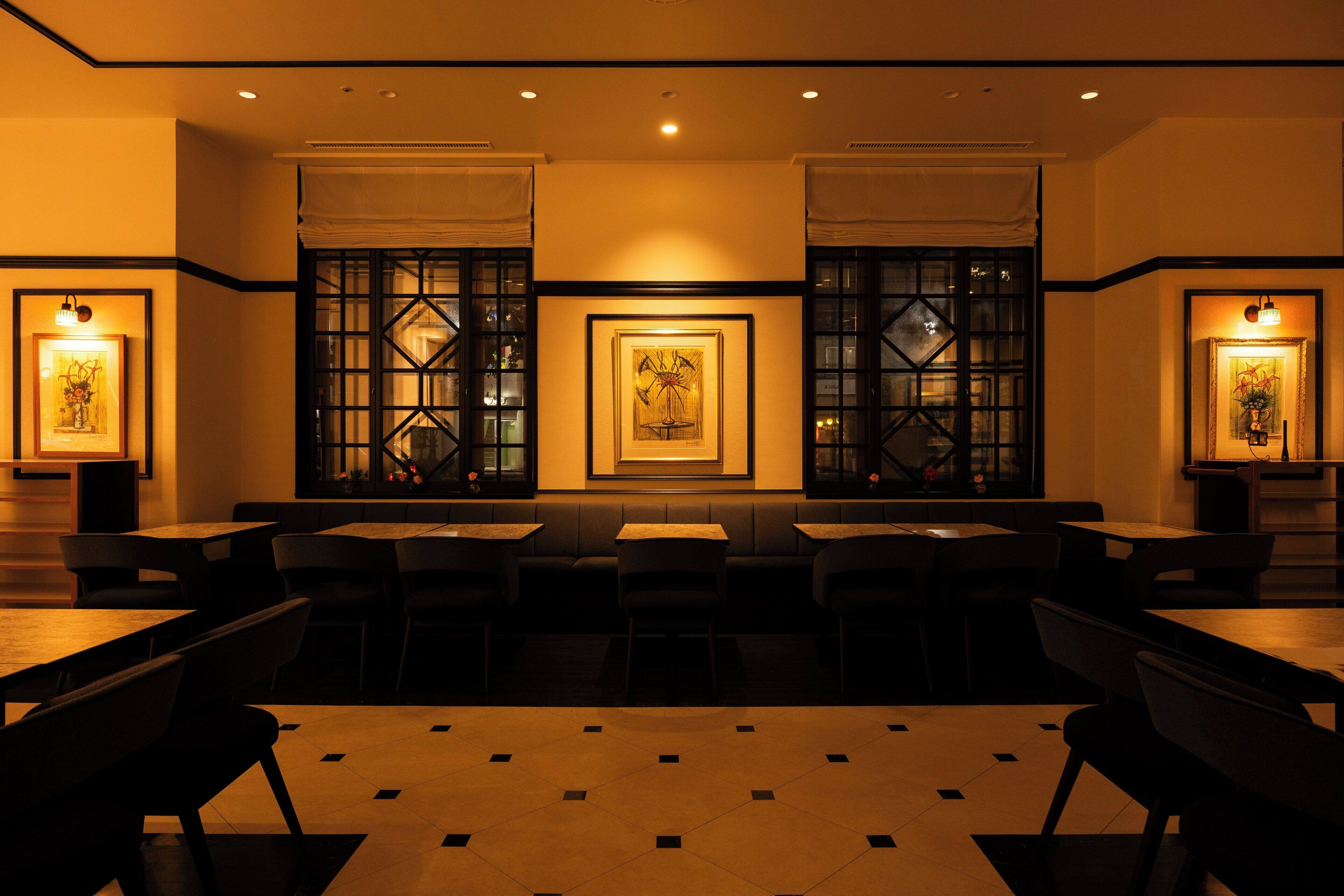 Interior de restaurant amb seients en cabines i taules, obres d'art als murs i il·luminació encastada al sostre.