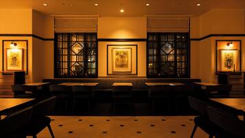 A restaurant interior with booths and tables, framed artwork on the walls, and recessed ceiling lighting.