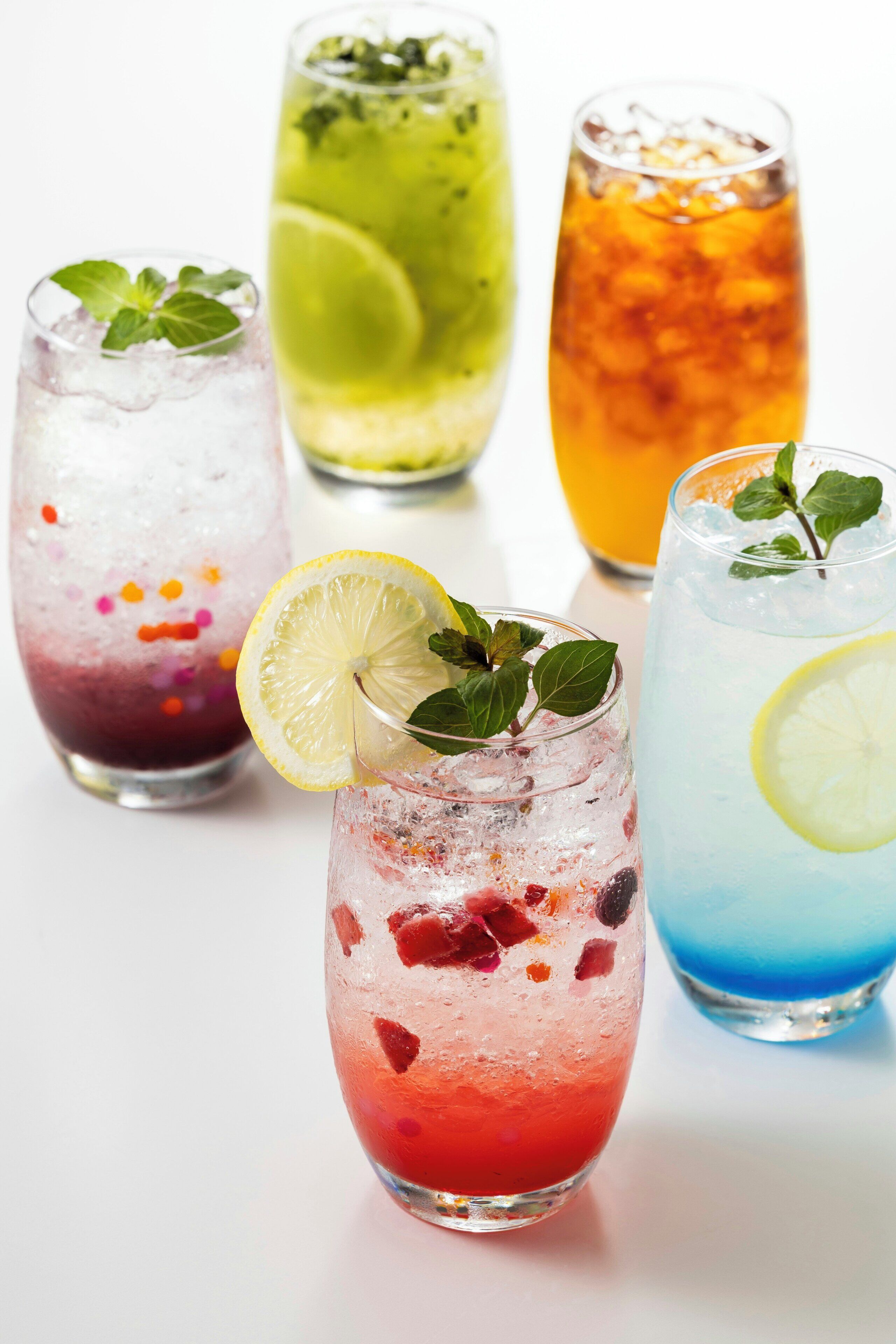 Une variété de boissons colorées servies dans des verres avec des glaçons et des décorations.