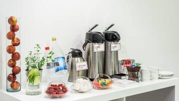 En drikkebuffet med forskellige automater, et glas med æbler og beholdere med snacks.