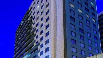 Un hotel de gran altura con varios pisos, ventanas amplias y un letrero llamativo en la parte superior.