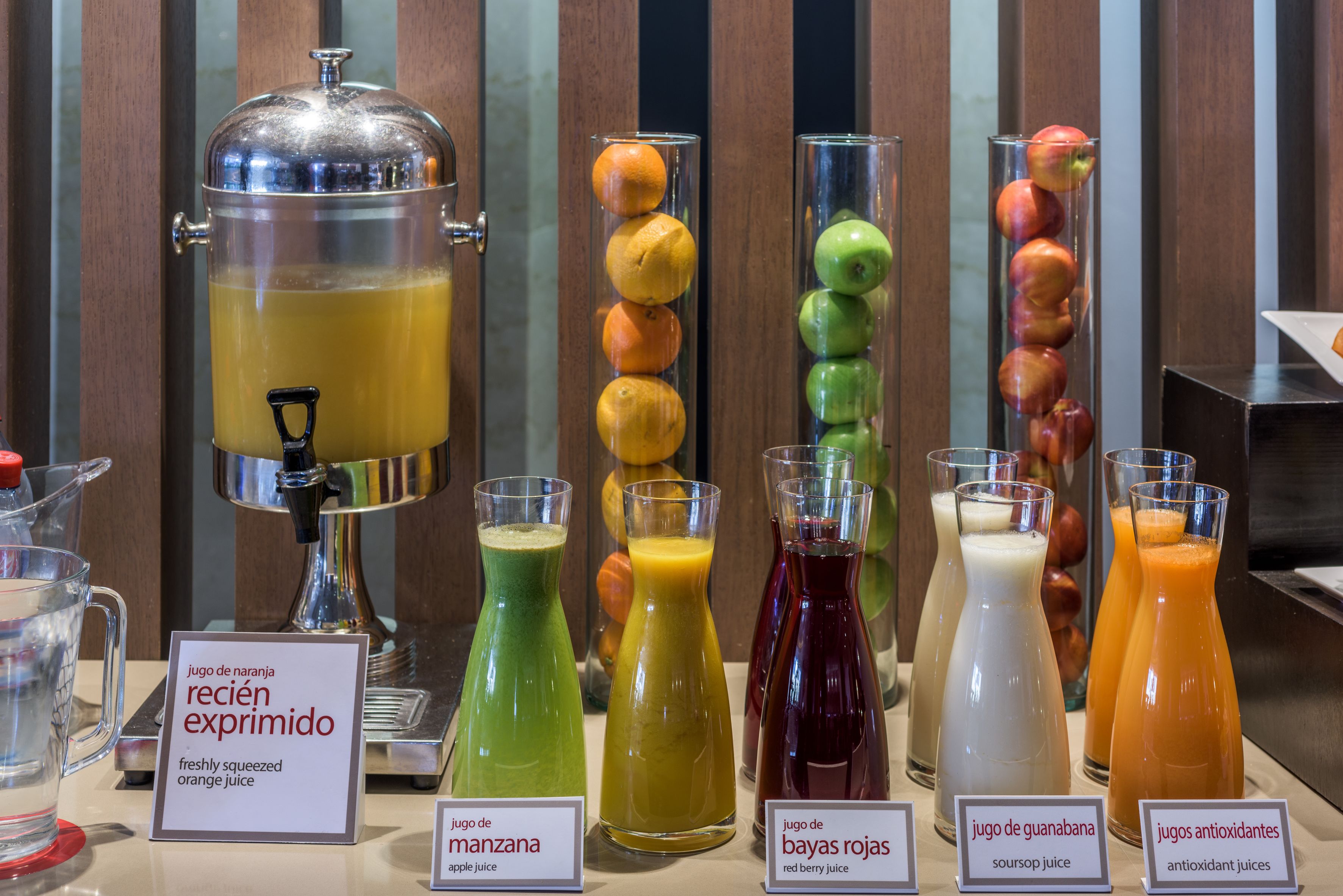 Un bar de zumos con diferentes jugos de frutas y un dispensador grande de ponche.