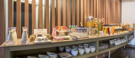 A buffet with various food and drink options, including yogurt, milk, and juice.