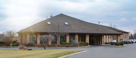 A brick building with a pitched roof, large windows, and a covered entrance.