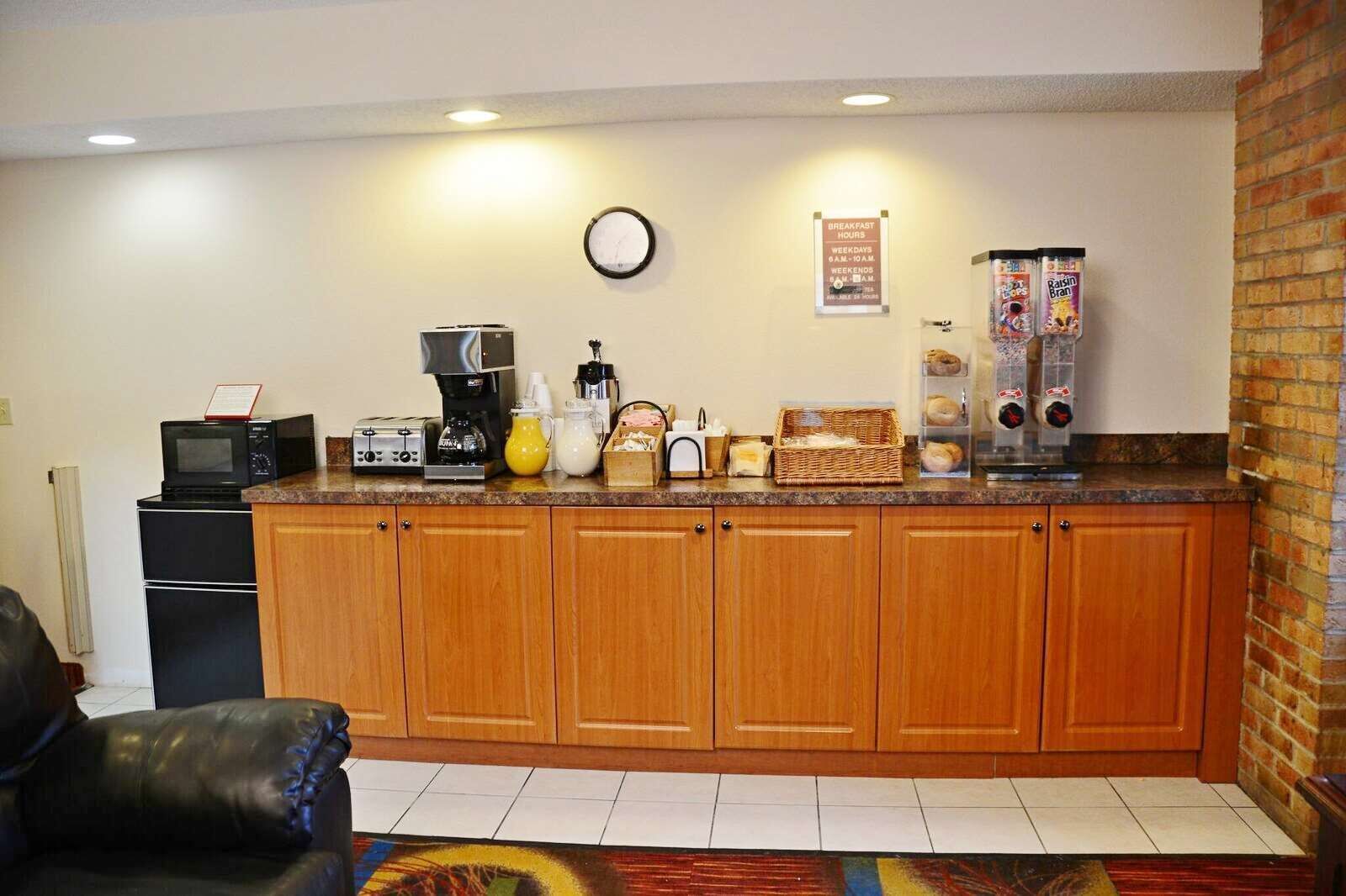 A compact kitchen with a microwave, toaster, coffee maker, and a breakfast sign.