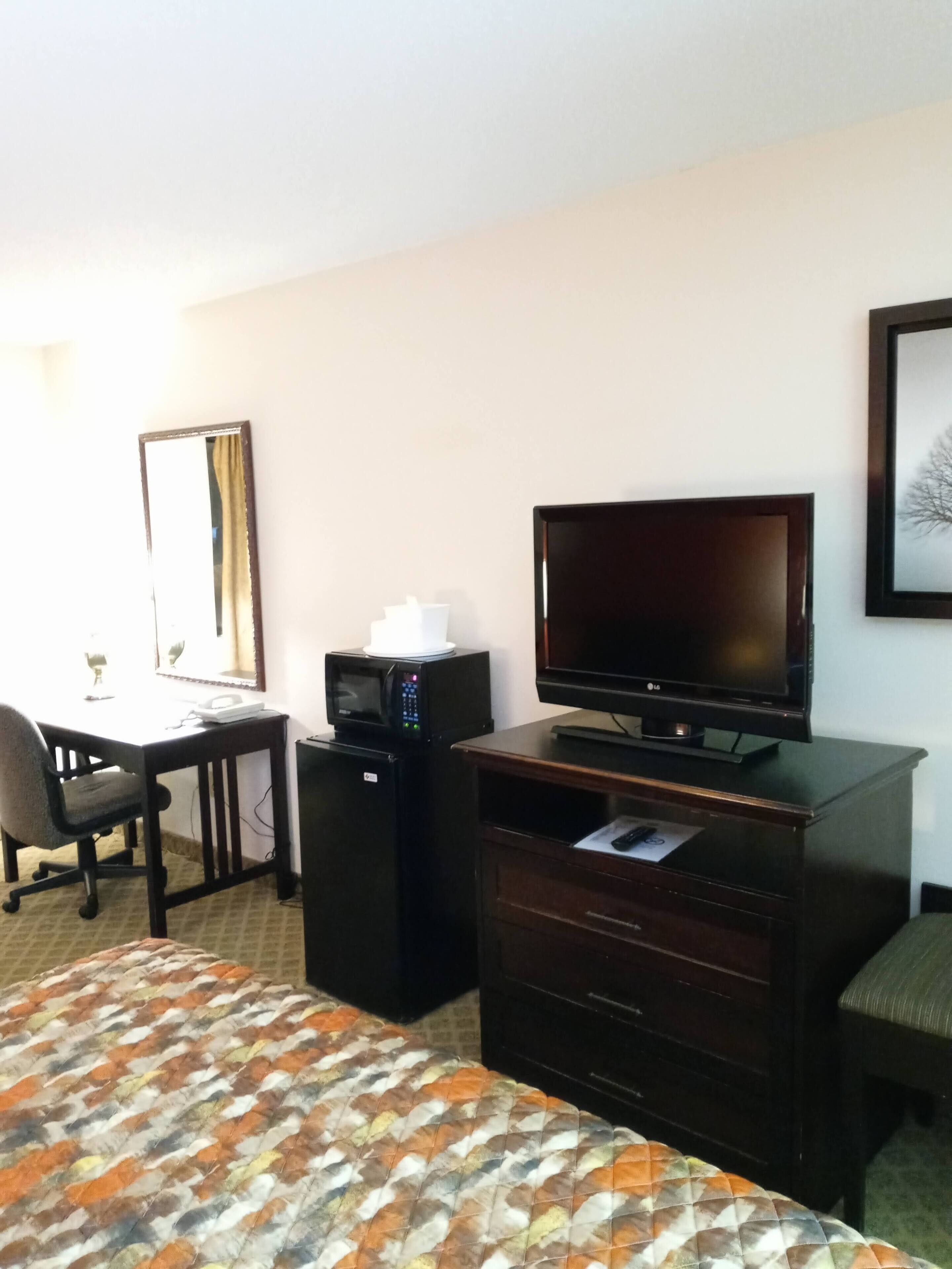 Ein Hotelzimmer mit Bett, Schreibtisch mit Computer, Fernseher und Mikrowelle.