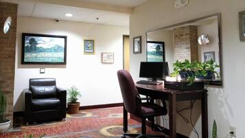 A room with a desk, chair, computer, and two potted plants.
