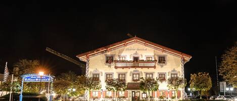 Un edificio histórico con balcón, cartel y entrada bien iluminada.