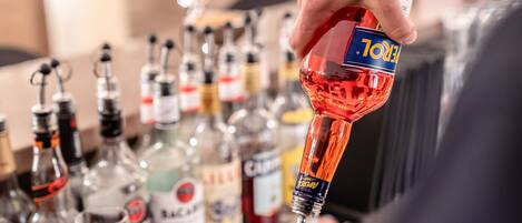 A hand pouring a red liquid from a bottle into a glass.
