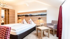 A modern hotel room with a large bed, a small table, a chair, and a painting on the wall. - Hotel Sauerlacher Post (Sauerlach)