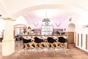 Una zona de bar con pared de cuero de vaca, candelabro y adornos de cuernos.