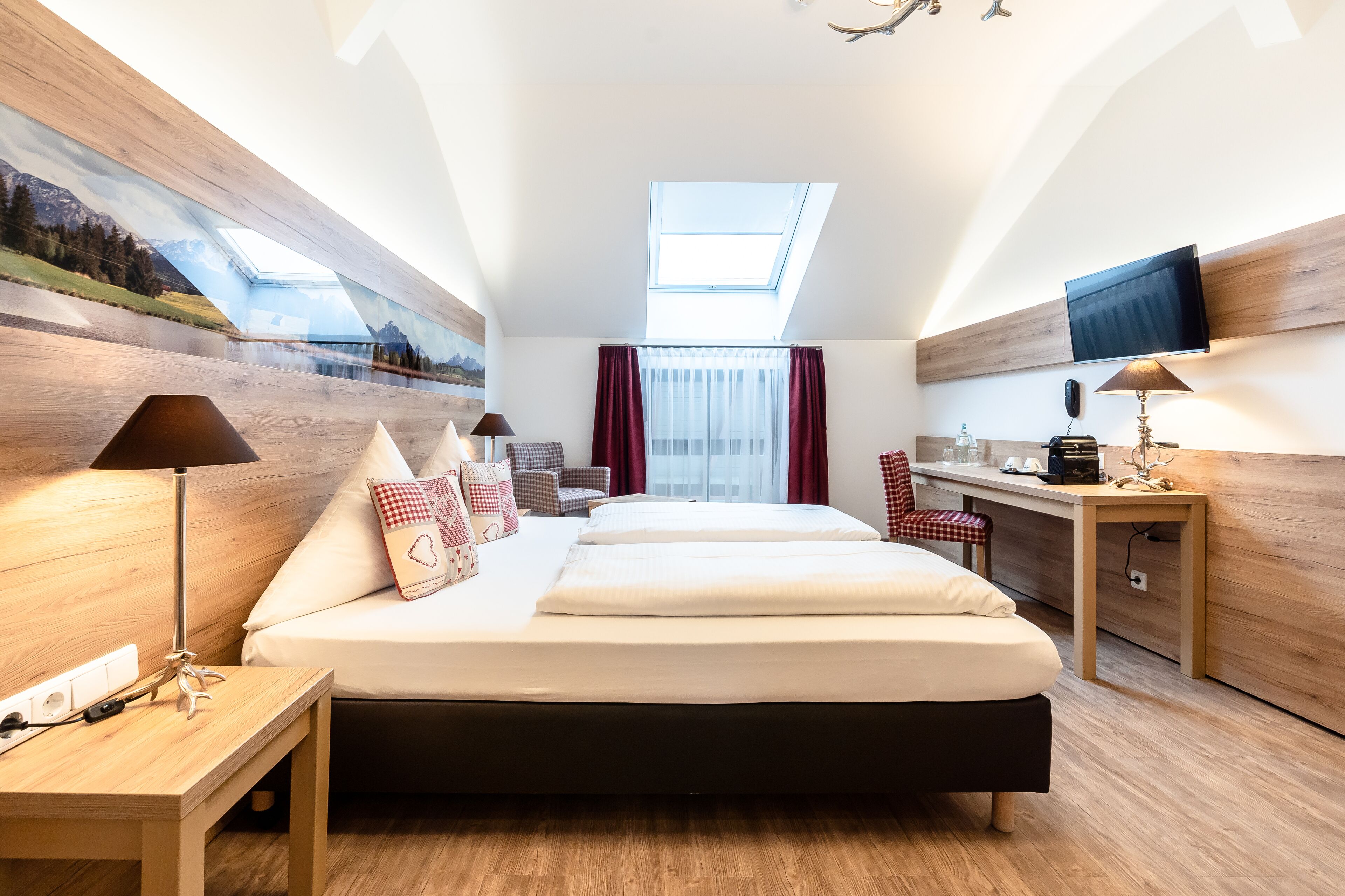 Quarto de hotel moderno com uma cama grande, uma escrivaninha, uma cadeira e uma televisão.