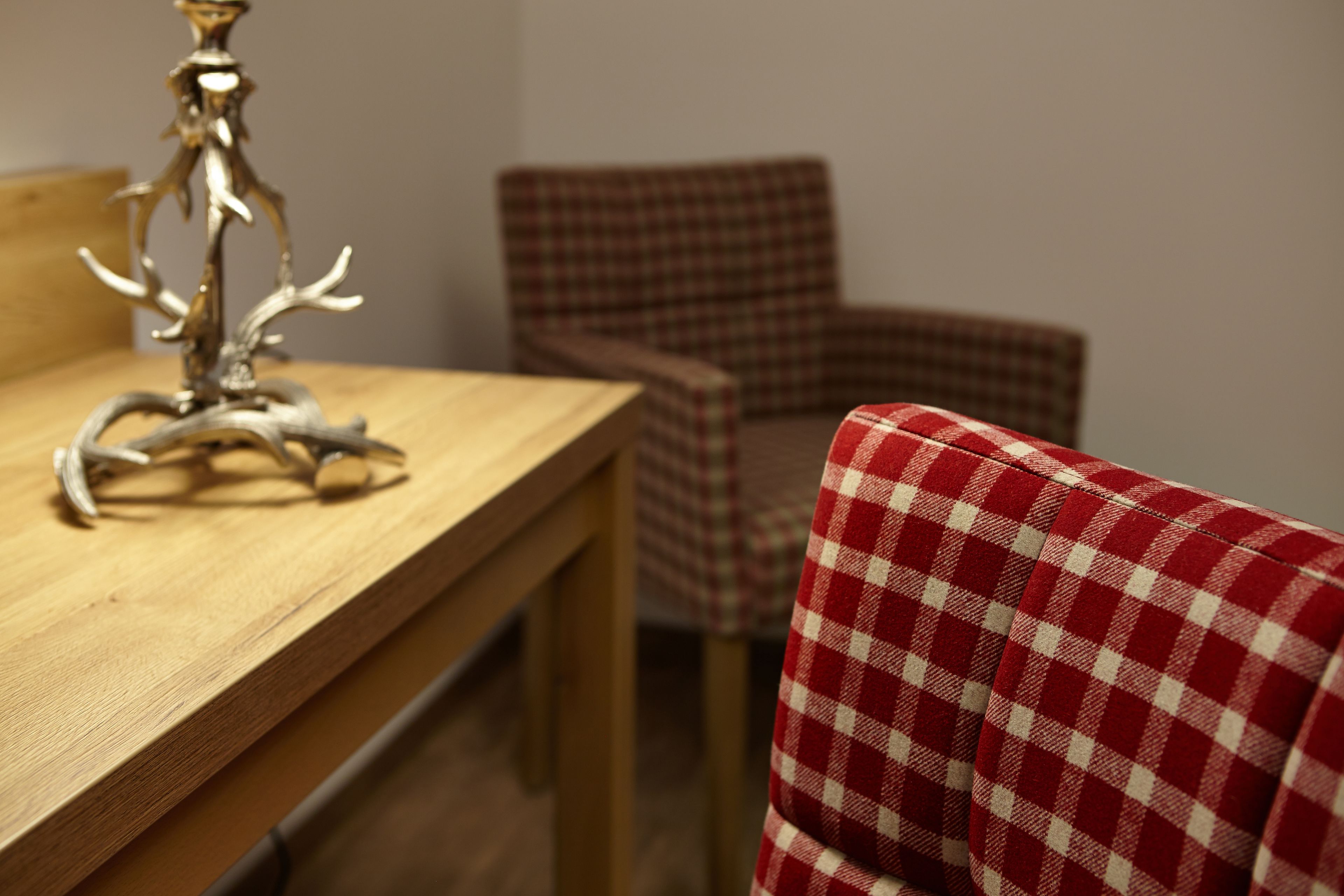 A dining table with a metal sculpture centerpiece, a plaid chair, and a red and white checkered fabric.