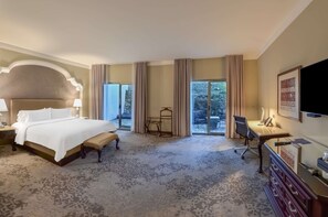 Une chambre d’hôtel avec un grand lit, un bureau et une chaise. Il y a une fenêtre avec des rideaux et une vue sur l’extérieur.