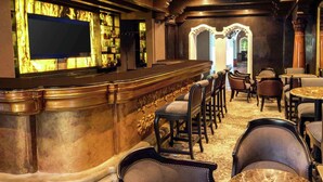 A bar area with a counter, bar stools, and a seating area with round tables and chairs.