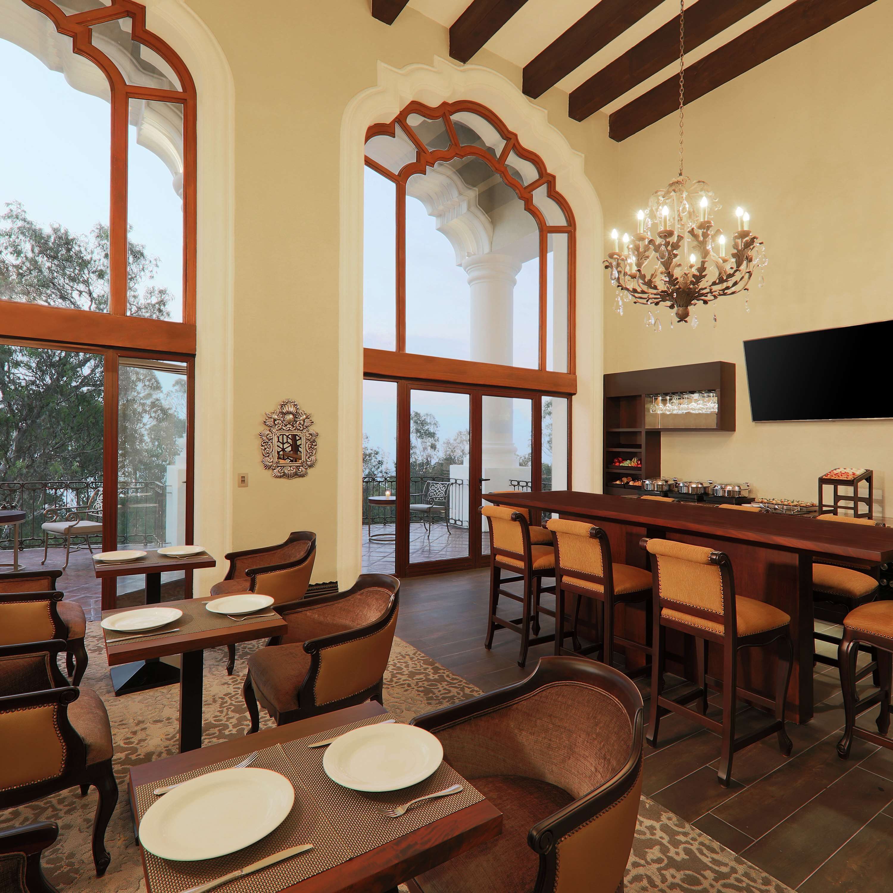 A dining area with wooden furniture, large windows, and a chandelier.